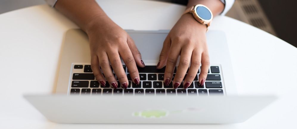 Woman wearing a gold watch typing on a laptop computer