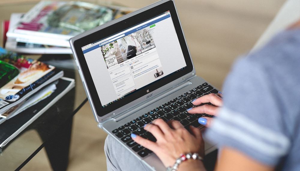 Woman on laptop updating Facebook